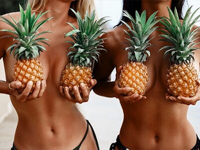 topless models holding pineapples over their boobs